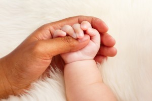 Adopted baby holding mother's hand
