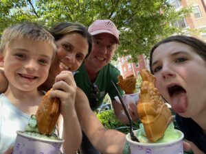 Jess and Elena with their adoptive son and daughter making funny faces while enjoying some ice cream.